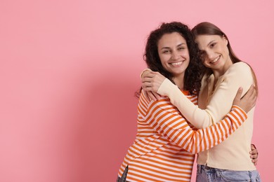 Photo of Two happy friends hugging on pink background, space for text