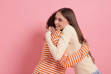 Photo of Two happy friends hugging on pink background, space for text