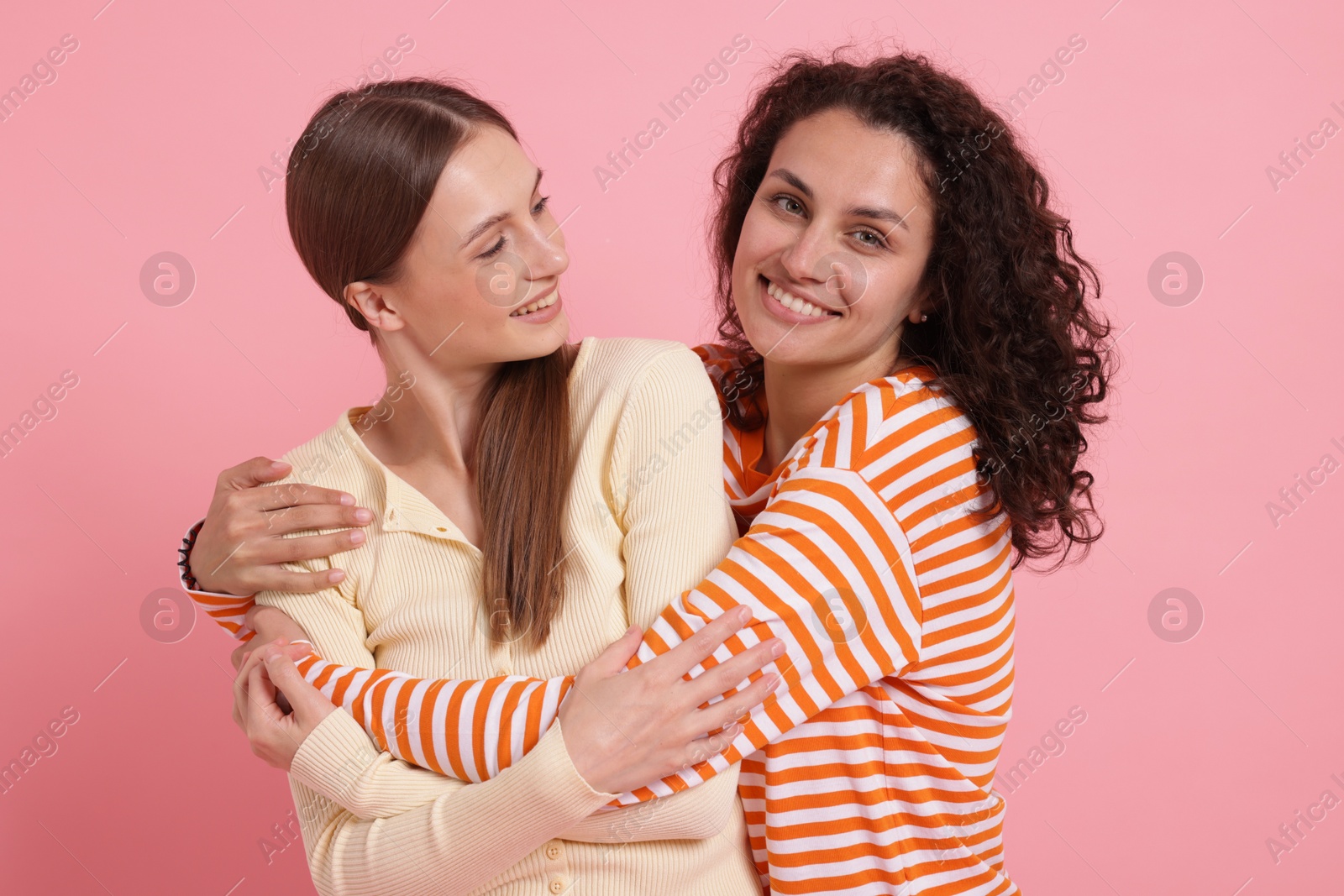 Photo of Friends hugging each other on pink background