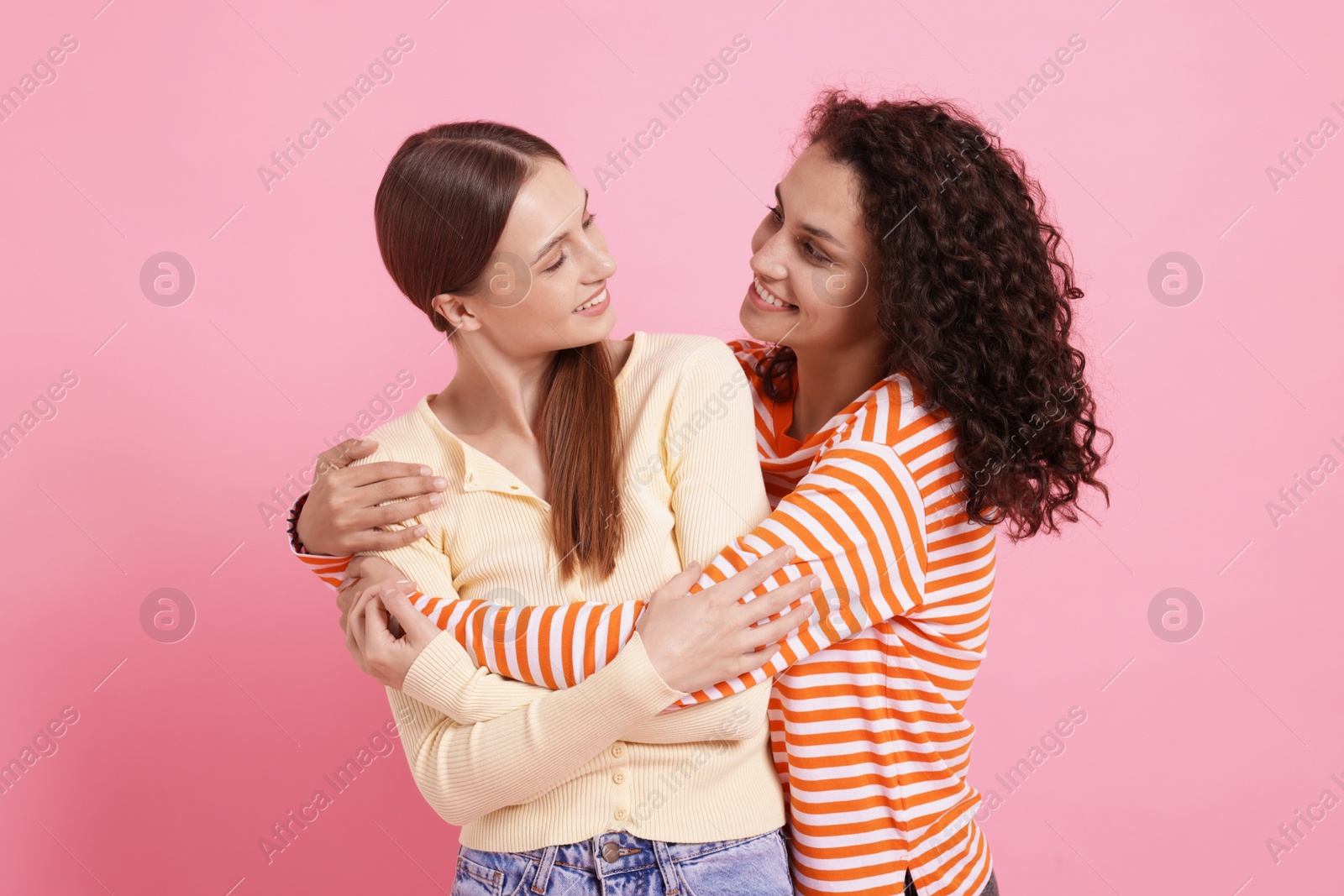 Photo of Friends hugging each other on pink background