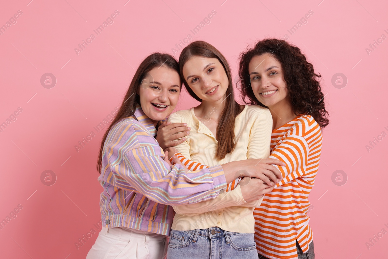 Photo of Friends hugging each other on pink background