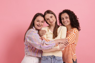 Photo of Friends hugging each other on pink background