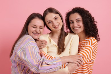 Photo of Friends hugging each other on pink background