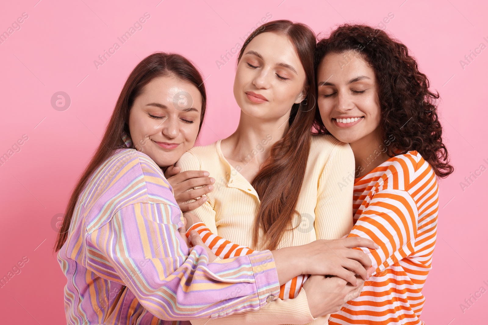 Friends hugging each other on pink background Photo of Friends hugging each other on pink background