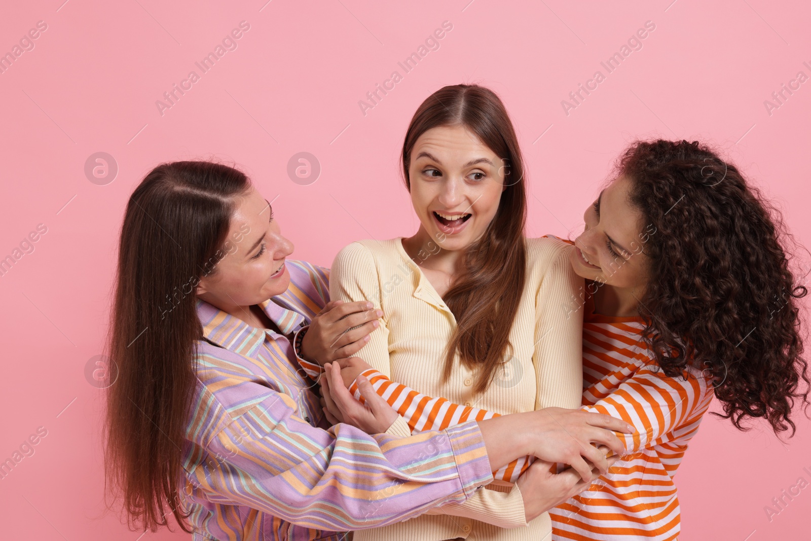 Photo of Friends hugging each other on pink background