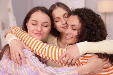Photo of Three friends hugging each other at home