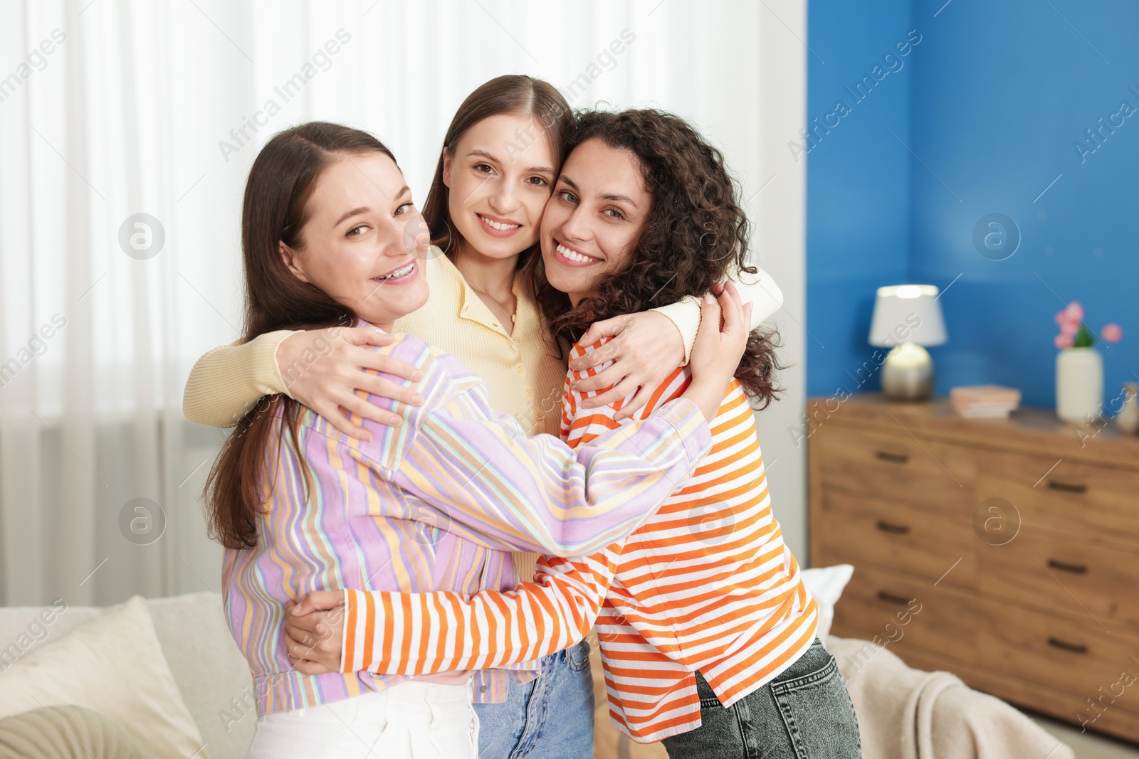 Photo of Three friends hugging each other at home