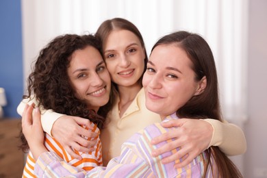 Photo of Three friends hugging each other at home