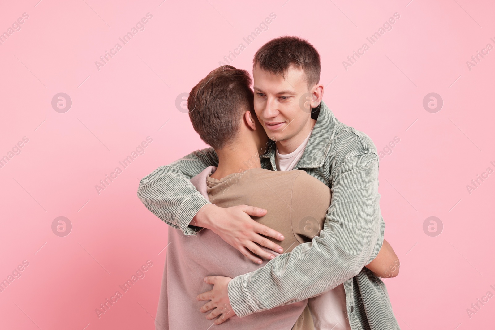 Two happy friends hugging on pink background Photo of Two happy friends hugging on pink background