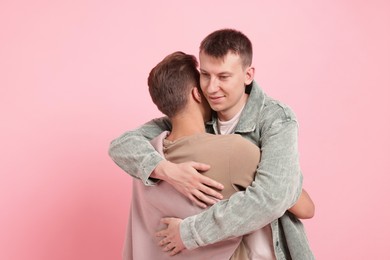 Photo of Two happy friends hugging on pink background