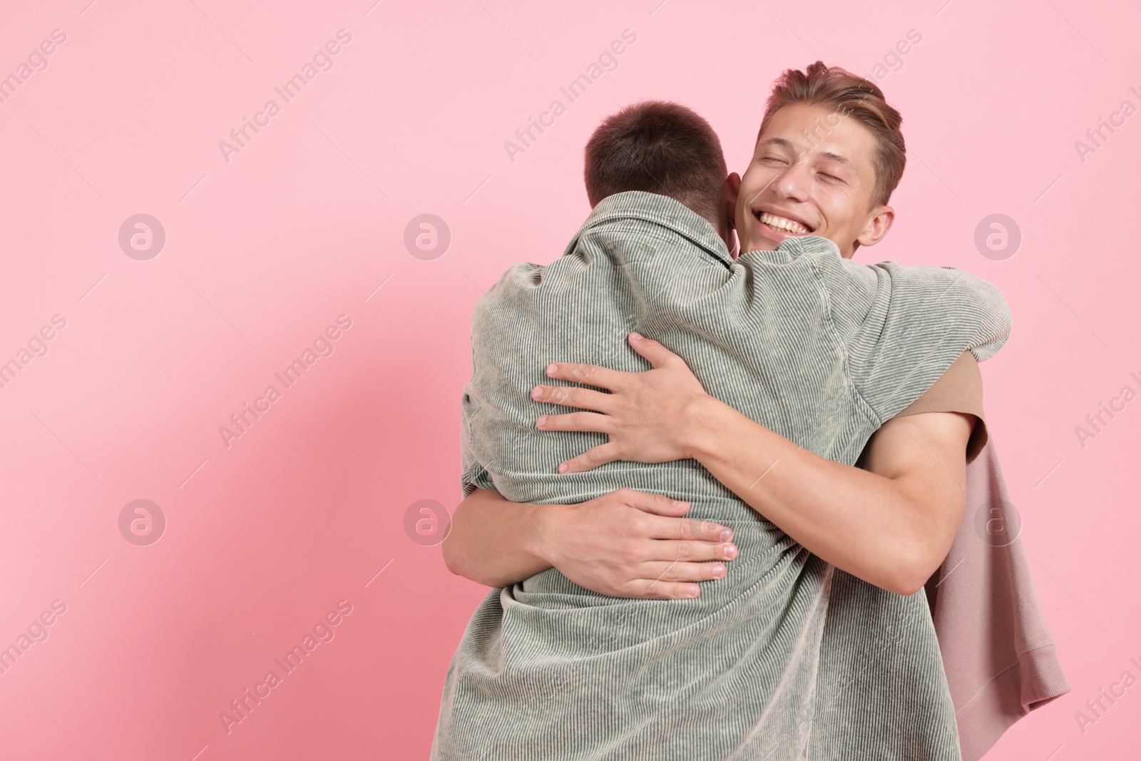 Two happy friends hugging on pink background, space for text Photo of Two happy friends hugging on pink background, space for text