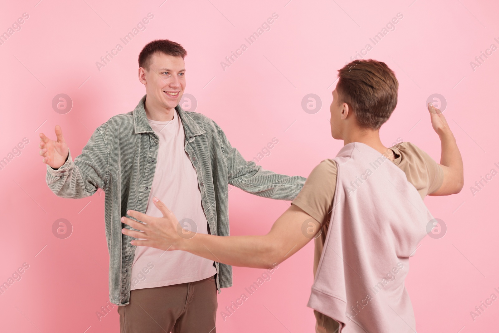 Friends welcoming each other on pink background Photo of Friends welcoming each other on pink background