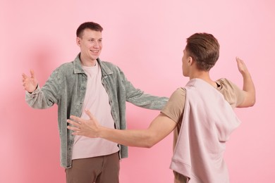 Photo of Friends welcoming each other on pink background