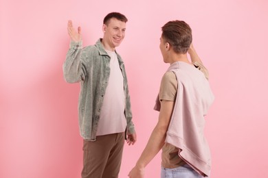 Photo of Friends welcoming each other on pink background