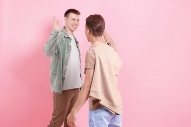 Photo of Friends welcoming each other on pink background