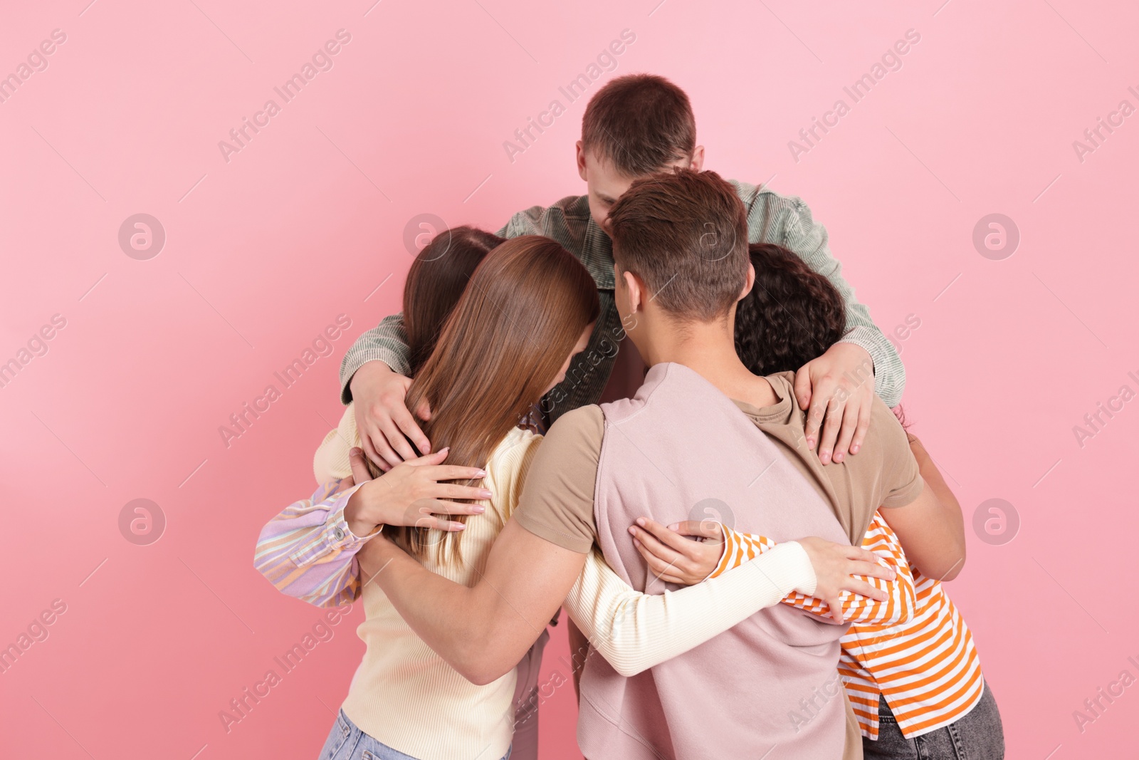 Photo of Group of friends hugging each other on pink background