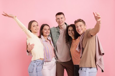 Photo of Group of friends hugging each other on pink background
