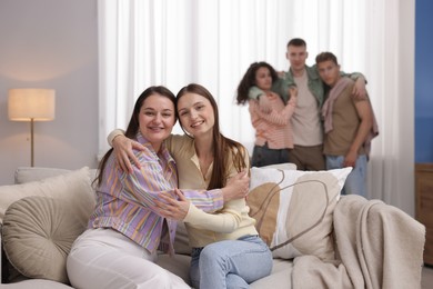 Photo of Friends hugging on sofa indoors, selective focus