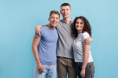 Photo of Three friends hugging on light blue background