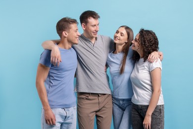 Photo of Group of friends hugging on light blue background