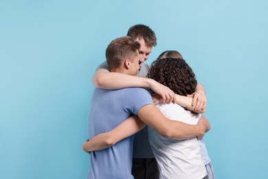 Photo of Group of friends hugging on light blue background