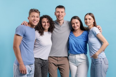 Photo of Group of friends hugging on light blue background