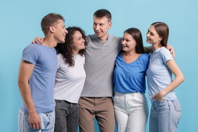 Photo of Group of friends hugging on light blue background