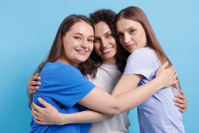 Photo of Three friends hugging on light blue background