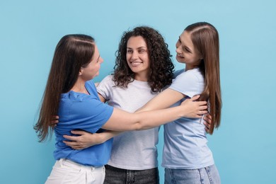 Photo of Three friends hugging on light blue background