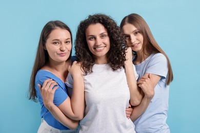 Photo of Three friends hugging on light blue background