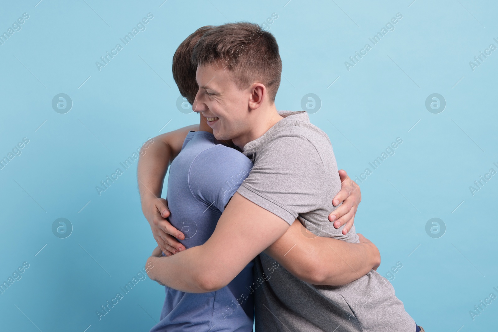 Photo of Two friends hugging on light blue background