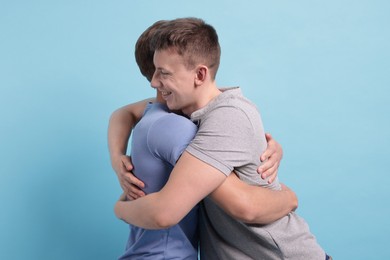 Photo of Two friends hugging on light blue background
