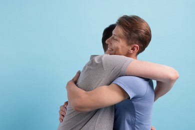 Photo of Two friends hugging on light blue background, space for text
