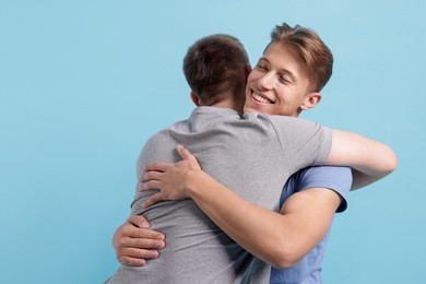 Photo of Two friends hugging on light blue background