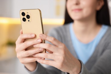 Photo of Woman using modern smartphone at home, selective focus