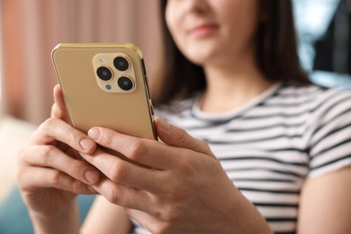 Photo of Woman using modern smartphone at home, closeup