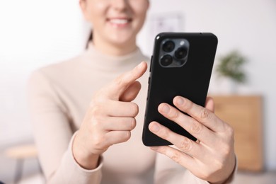 Photo of Woman using modern smartphone at home, closeup