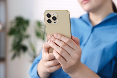 Photo of Woman using modern smartphone at home, closeup. Space for text