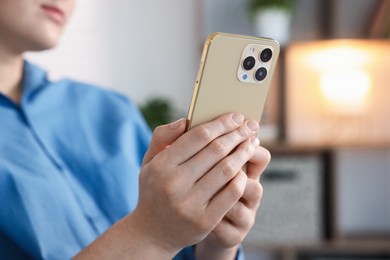 Photo of Woman using modern smartphone at home, closeup