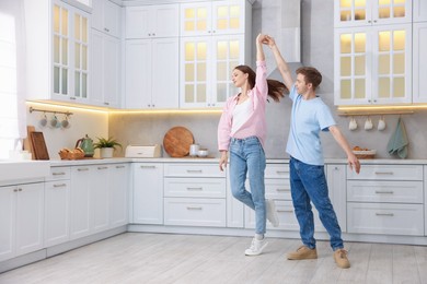 Photo of Happy young couple dancing together in kitchen