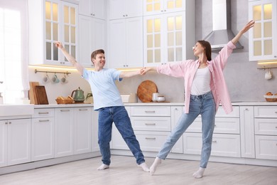 Photo of Happy young couple dancing together in kitchen