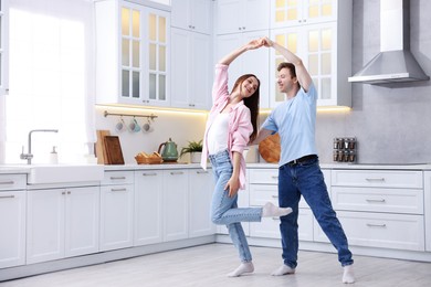 Photo of Happy young couple dancing together in kitchen