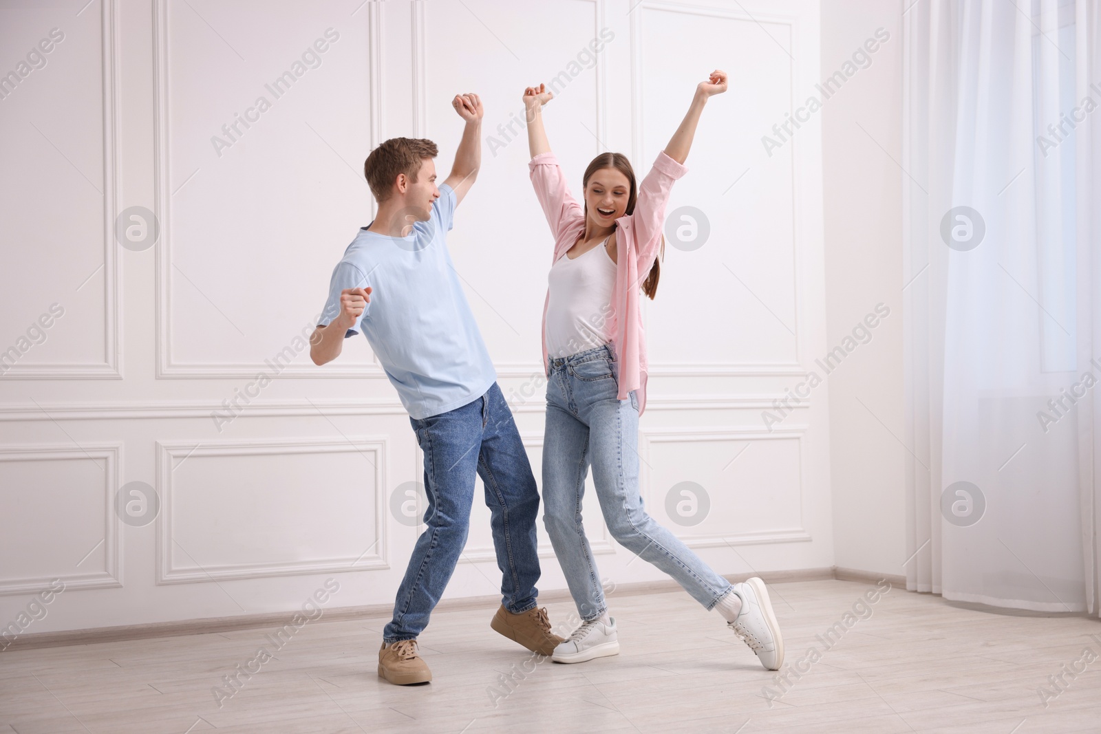 Happy couple dancing together near white wall at home Photo of Happy couple dancing together near white wall at home