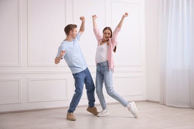 Photo of Happy couple dancing together near white wall at home