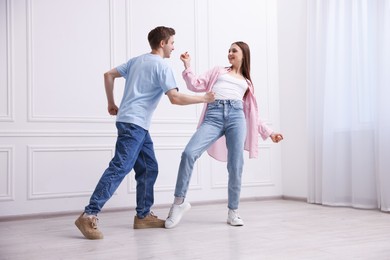 Photo of Happy couple dancing together near white wall at home