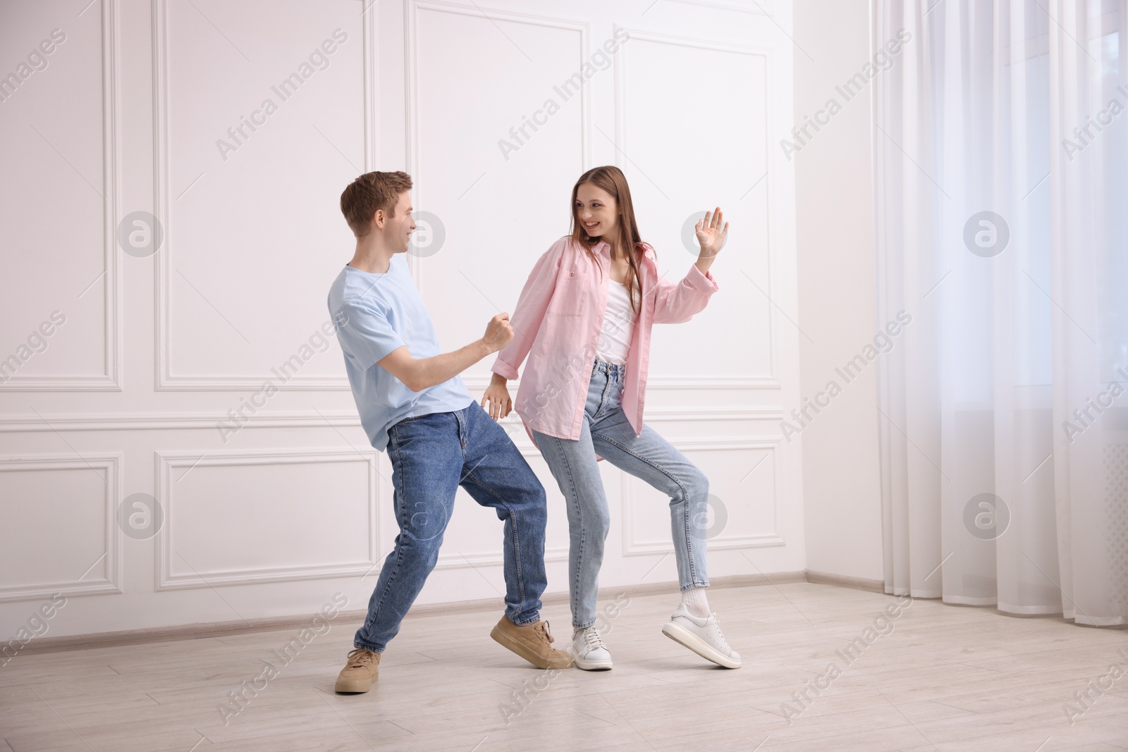 Happy couple dancing together near white wall at home Photo of Happy couple dancing together near white wall at home
