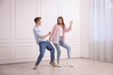 Photo of Happy couple dancing together near white wall at home