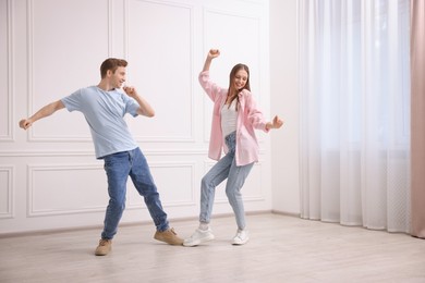 Photo of Happy couple dancing together near white wall at home
