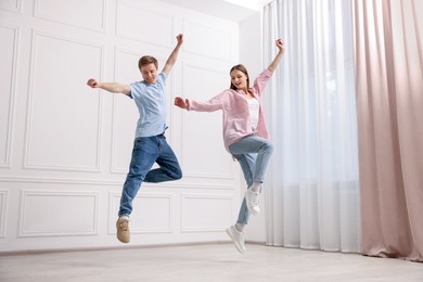 Photo of Happy couple dancing together near white wall at home, low angle view