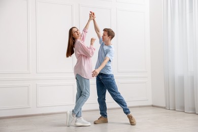 Photo of Happy couple dancing together near white wall at home